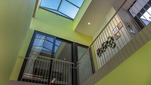 Un intérieur moderne avec un plafond haut, des fenêtres de toit et un balcon doté d’une balustrade.