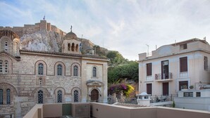 Une cour offrant une vue sur des bâtiments historiques en pierre, un petit clocher et un immeuble moderne doté de balcons.