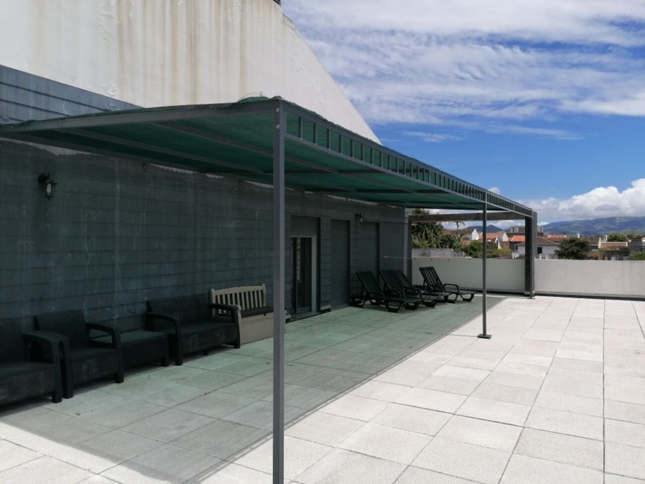 A rooftop terrace with outdoor seating and a covered area.
