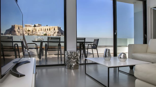 Une chambre moderne avec un balcon, une table blanche et un canapé.