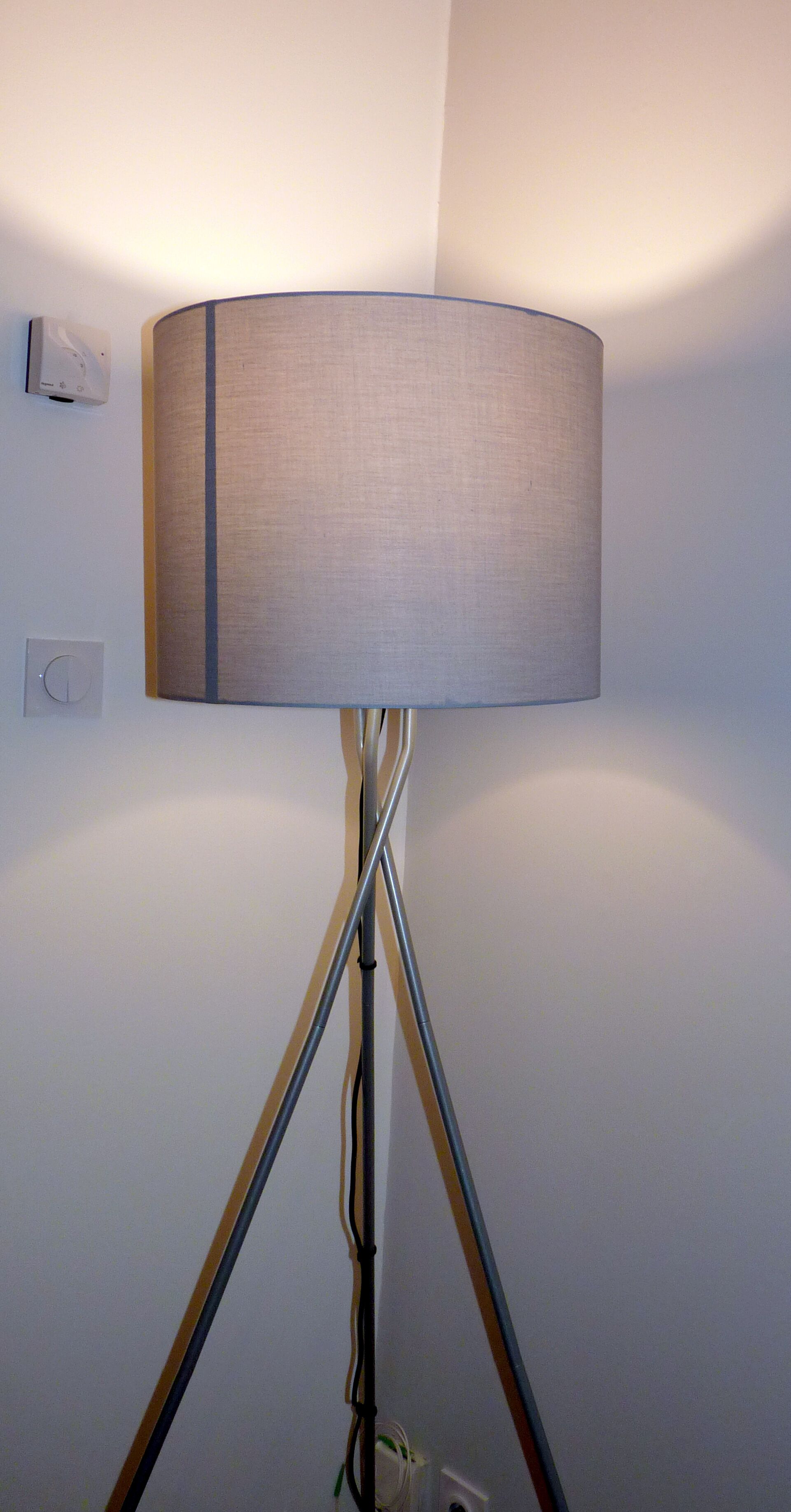 Un lampadaire doté d’un abat-jour cylindrique et d’un pied en métal.
