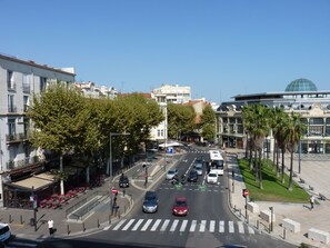 Straßenansicht mit Zebrastreifen, Autos und Palmen.