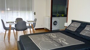 Ein modernes Zimmer mit Essbereich, einer Waschmaschine und einer Couch mit markenbezogenen Kissen.