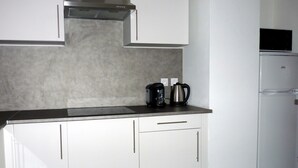 Eine Küche mit weißen Schränken, einem Edelstahl-Dunstabzug und einer Kaffeemaschine auf der Arbeitsplatte.