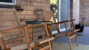 A wicker sofa and a wooden chair with metal legs, positioned on a yellow patterned rug. - Mrs Brightside - Tucked away in a quiet side street, Mrs. Brightside's location is sure to impress. (BRIGHT)