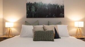 A neatly made bed with white bedding, multiple pillows, and two bedside lamps on wooden stands. - Mrs Brightside - Tucked away in a quiet side street, Mrs. Brightside's location is sure to impress. (BRIGHT)