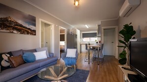A modern living room with a grey sofa, a glass coffee table, and a TV. - Mrs Brightside - Tucked away in a quiet side street, Mrs. Brightside's location is sure to impress. (BRIGHT)