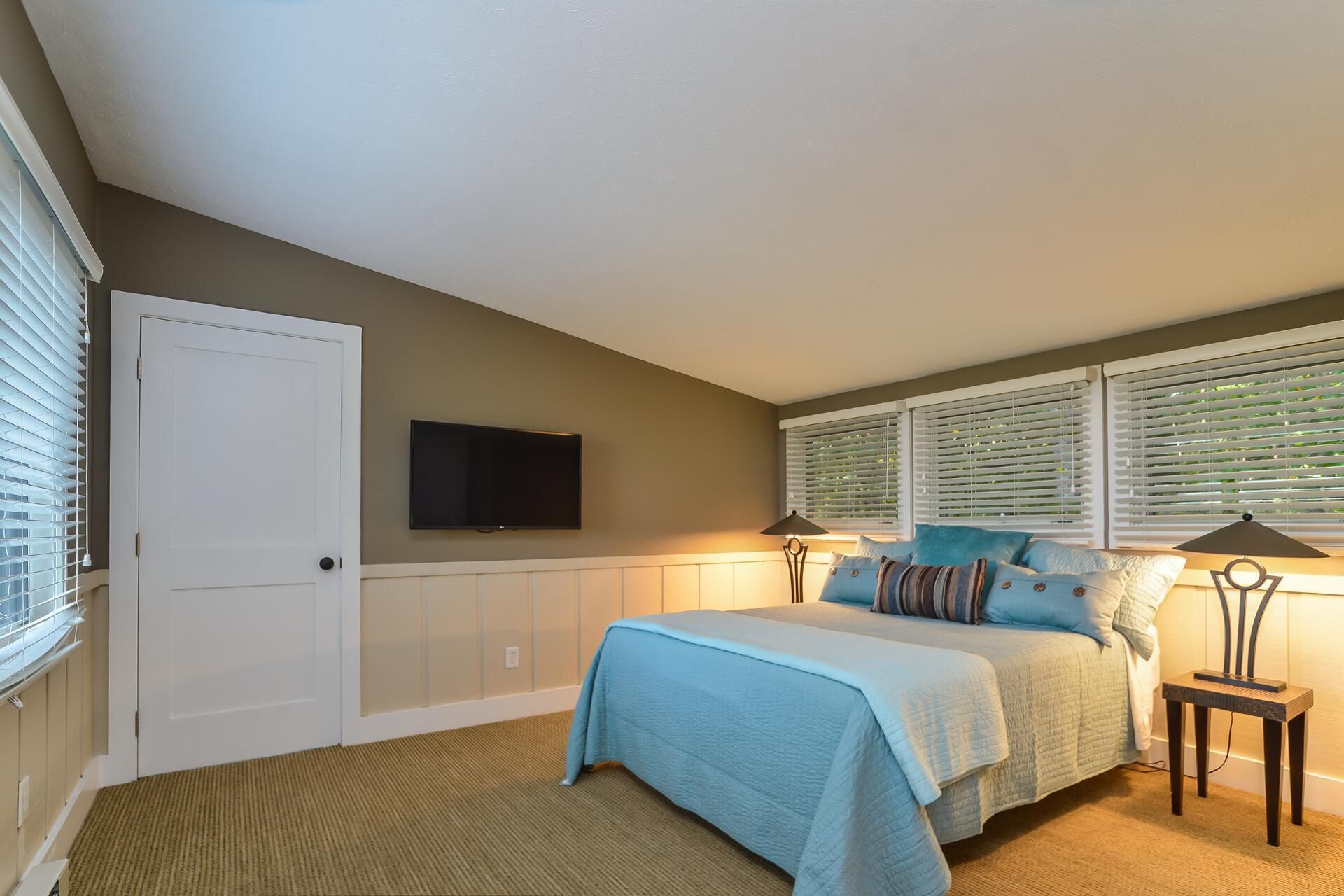 A bedroom with a bed, a TV, and two lamps.