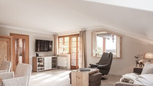 Een gezellige woonkamer met een houten kast, een massagestoel, een bank en een televisie.