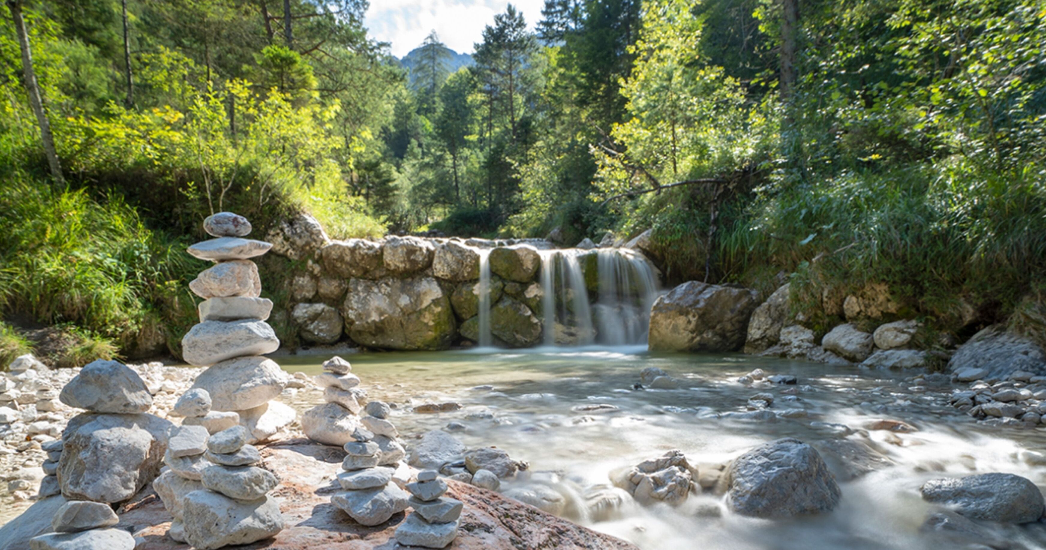 Un paysage naturel comprenant une cascade, un amas de rochers et une rivière.