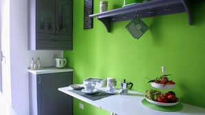 Une cuisine avec un mur vert, un plan de travail blanc et un coin café.