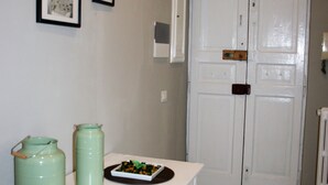 Une pièce avec une table blanche, deux récipients verts, un tableau encadré et une porte blanche.