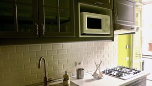 Une cuisine équipée d’un évier en acier inoxydable, d’un four à micro-ondes et d’une cuisinière à gaz.