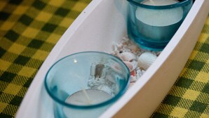 A white tray with two glass containers filled with ice and a candle, placed on a checkered tablecloth. - Apartments Briest - Studio Apartment (Dubrovnik)