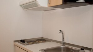 A compact kitchen with a sink, stove, and wooden cabinets. - Apartments Briest - Studio Apartment (Dubrovnik)