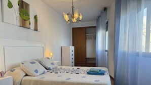 Une chambre à coucher bien aménagée, avec un lit, des tables de chevet, une armoire et un lustre.