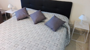 A neatly made bed with a patterned bedspread and three pillows, flanked by two bedside tables with lamps. - Sistina House near Spanish Steps (Roma)