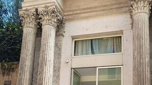 A building entrance with classical columns, a glass door, and a visible interior with a staircase. - Sistina House near Spanish Steps (Roma)