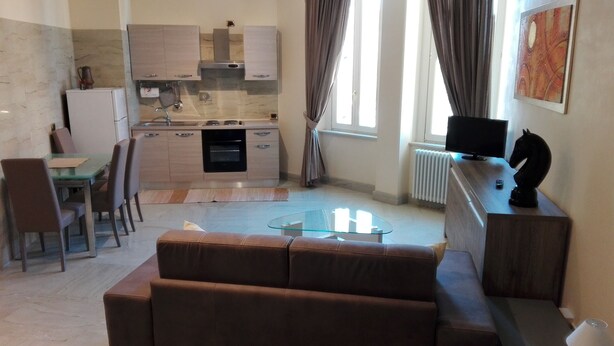 A modern living room with a glass coffee table, brown leather sofa, and a TV on a wooden stand. - Sistina House near Spanish Steps (Roma)