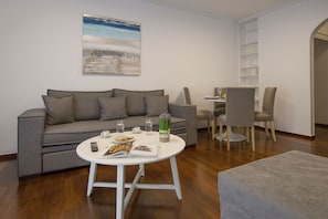 A modern living room with a grey sofa, a round coffee table, and a bookshelf.