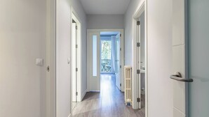 Ein Korridor mit weißen Wänden und Holzboden, der zu einem Balkon mit Tisch und Stühlen führt.