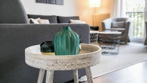 Ein Wohnzimmer mit grauem Sofa, einem runden Beistelltisch mit einer dekorativen Vase und einem Couchtisch.