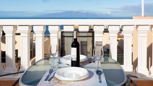 A table set for two with a bottle of wine, two wine glasses, and plates on a balcony overlooking a scenic view. - Arco Iris on the sea with pool (Callao Salvaje)