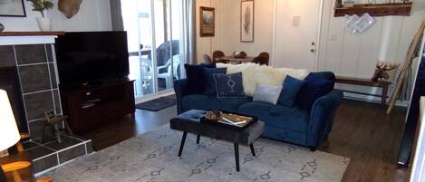 Una sala de estar con un sofá azul, una mesa de centro, un televisor y una chimenea.