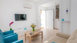 Uma sala de estar moderna com um sofá, uma mesa de centro e uma TV na parede.