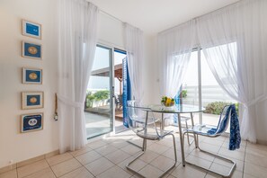 Ein moderner Raum mit Glastisch und Stühlen, Blick ins Freie und gerahmten Auszeichnungen an der Wand.