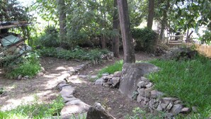 A garden pathway with a stone border, surrounded by lush greenery and trees.