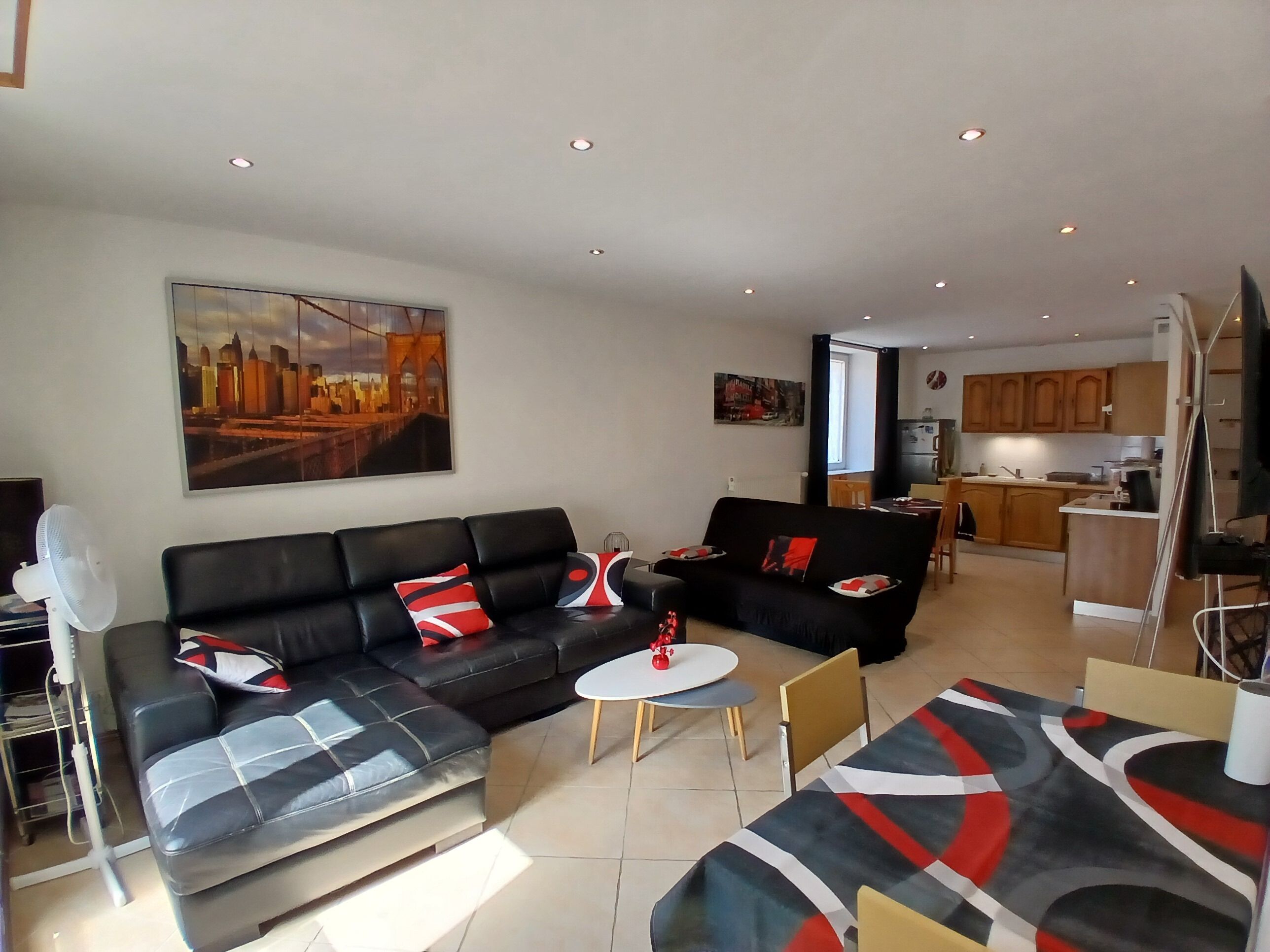 A modern living room with a sofa set, a dining table, and a kitchen area in the background.