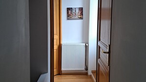 A hallway with a radiator, wooden door, and a painting on the wall. - Comfortable 2bed/ 6-person apartment (Saint-Rambert-en-Bugey)