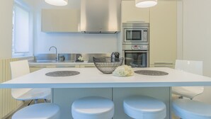 Een moderne keuken met een centraal eiland, barkrukken, een magnetron, oven en een roestvrijstalen afzuigkap.
