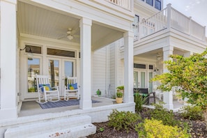 A two-story house with a covered porch, white exterior, and a small garden area.