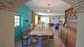 Un comedor con una larga mesa de madera, sillas y techo de ladrillo.