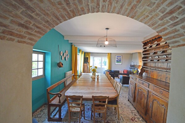 Un espace repas avec une longue table en bois, des chaises et un plafond en briques.
