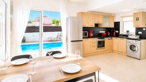 A modern kitchen with wooden cabinets, a built-in oven, and a washing machine. - Narcissos Villa Doria (Protaras)