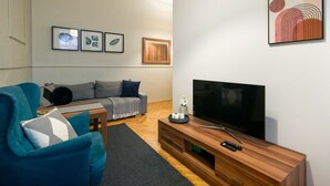 A modern living room with a sofa, a blue armchair, a coffee table, a TV, and framed artwork on the wall.