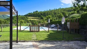 Ein Poolbereich mit Holzzaun, einem Steinweg und Blick auf einen bewaldeten Hügel.