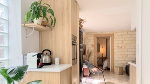 A modern kitchen with wooden cabinetry, a kettle, a coffee maker, and a plant. - Home Chic Home - La Terrasse Bazille (Montpellier)