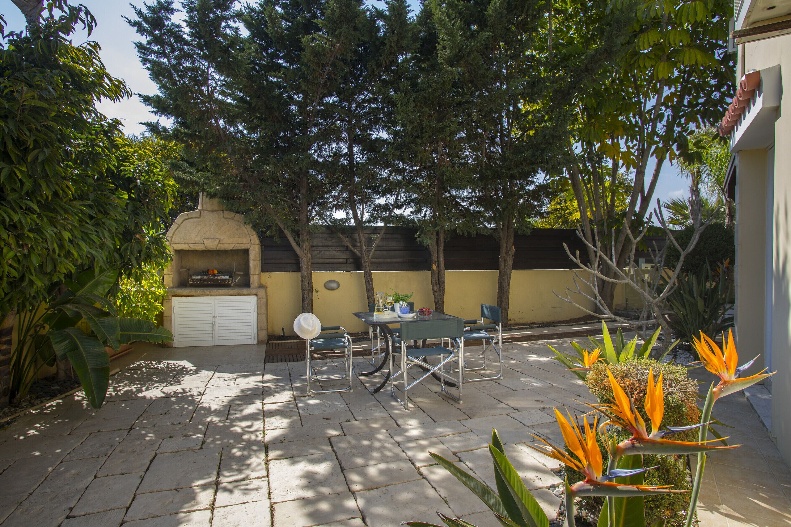 An outdoor patio with stone flooring, a grill, and a table with chairs.