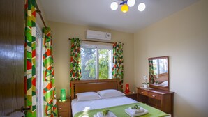 Un dormitorio con cama, mesita de noche, espejo y ventana con cortinas.