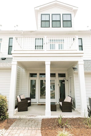 A two-story house with a covered porch, white siding, and a balcony.