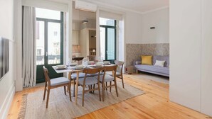 A modern living room with a dining area, a sofa, and a large window.