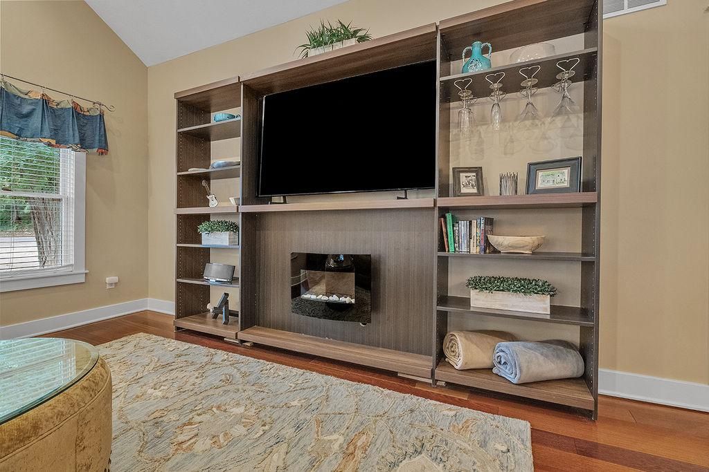 A living room with a flat-screen TV, a fireplace, and built-in shelves with decorative items.