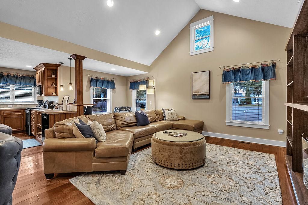 A spacious living area with a large L-shaped sofa, a round ottoman, and a kitchen in the background.