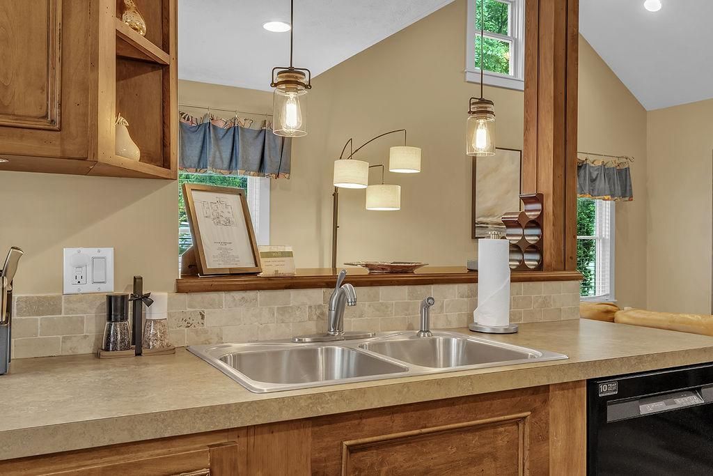 A kitchen with a double sink, wooden cabinets, a coffee maker, and a dishwasher.