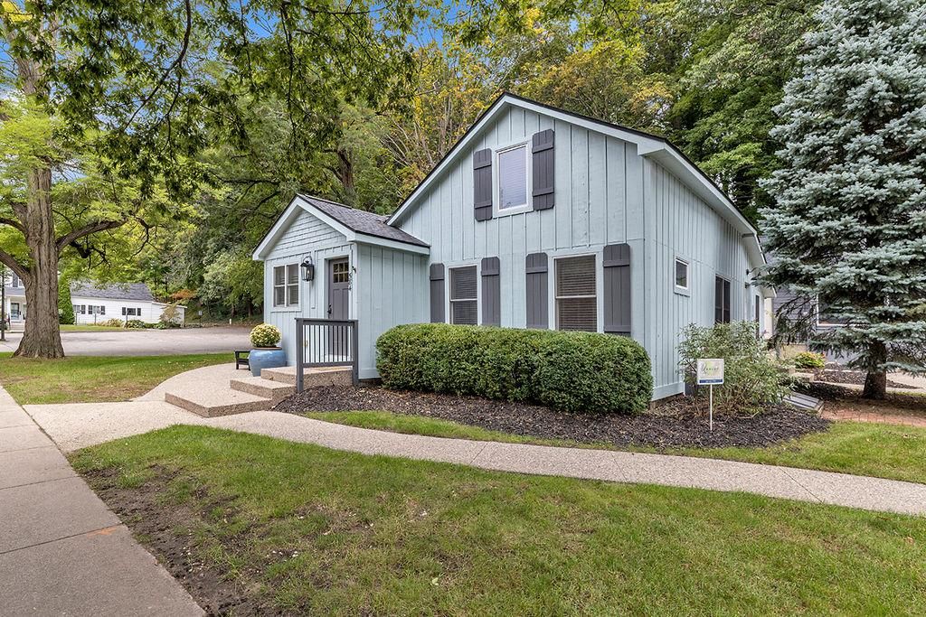 A two-story house with a front porch, a small attached garage, and a well-maintained lawn.