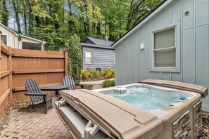 Un jardin avec un jacuzzi, une terrasse en bois et des fauteuils Adirondack.